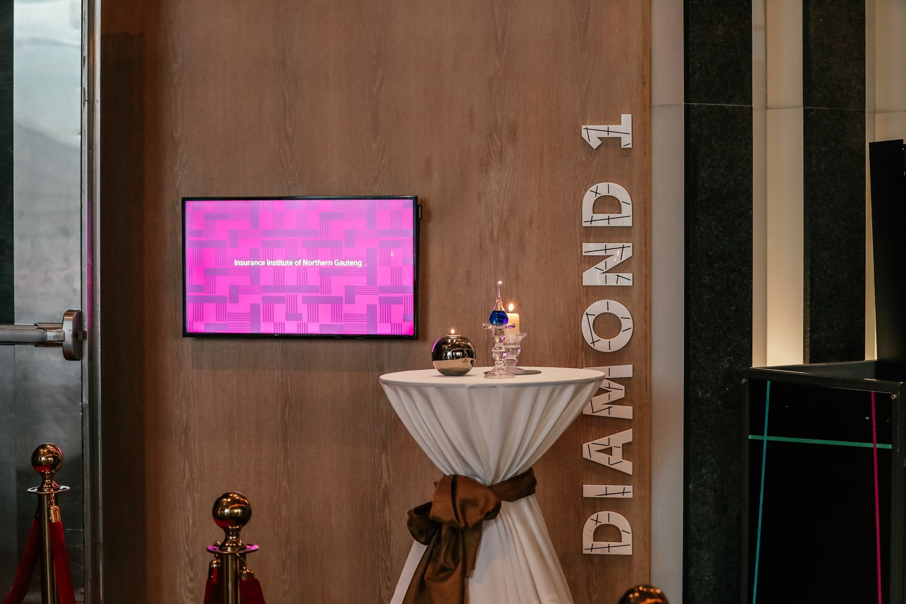 Foyer screen reading Insurance Institute of Northern Gauteng beside DIAMOND 1 lettering and a cocktail table