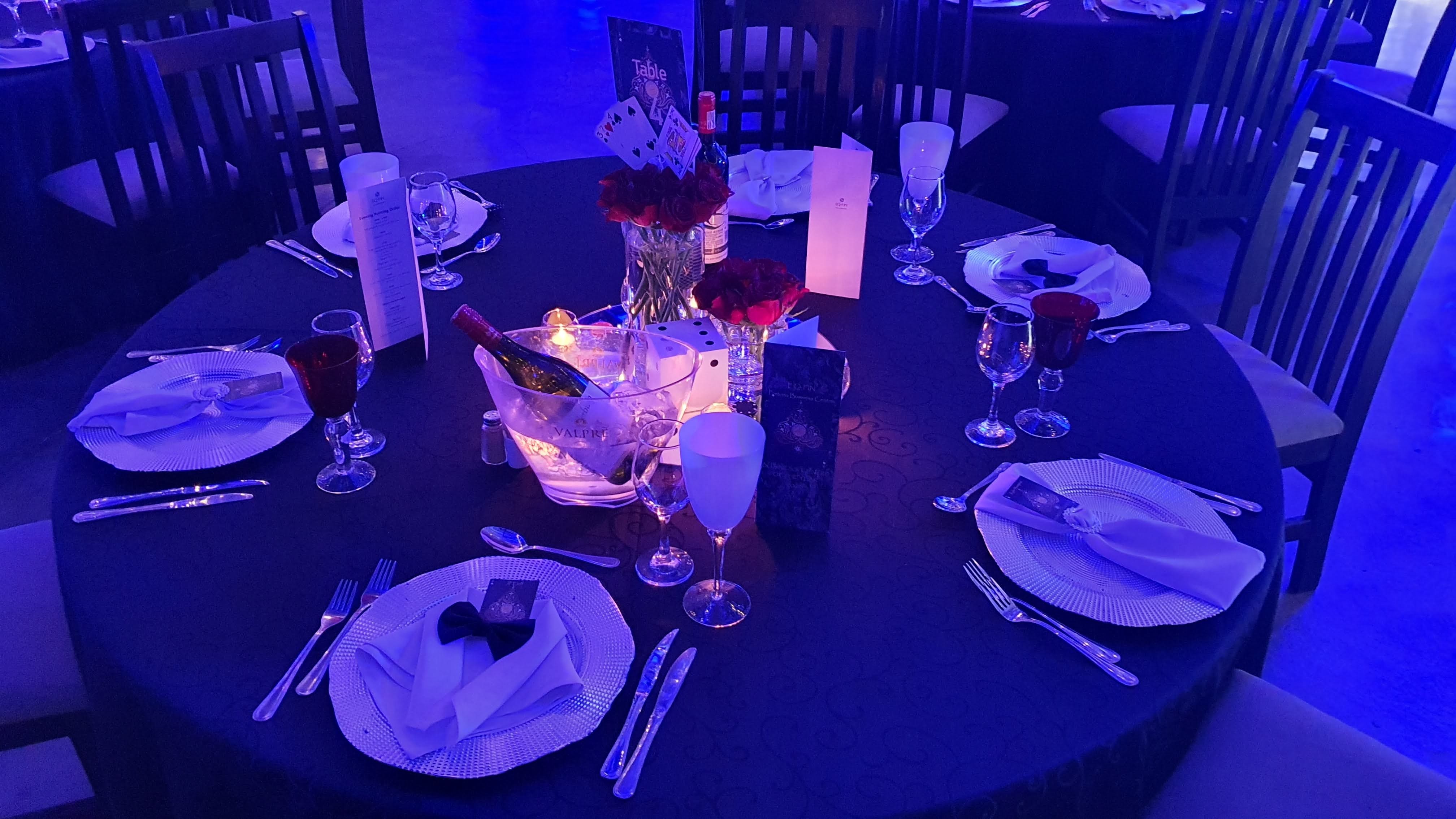 Place setting with an EQ-FIN menu card, a bowtie napkin fold, and Valpré sparkling water in an ice bucket