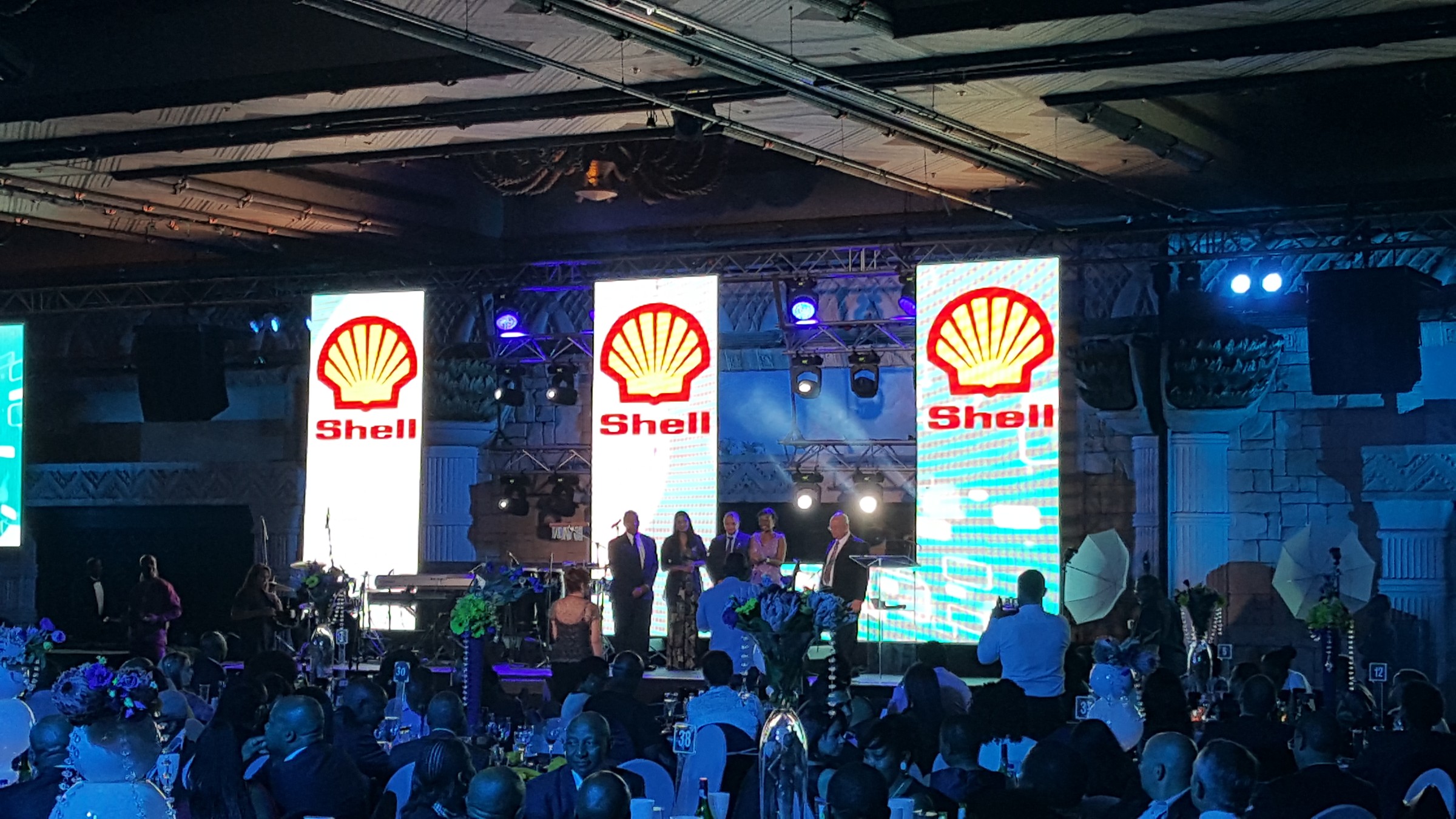 Three Shell pillars behind a group on the awards stage