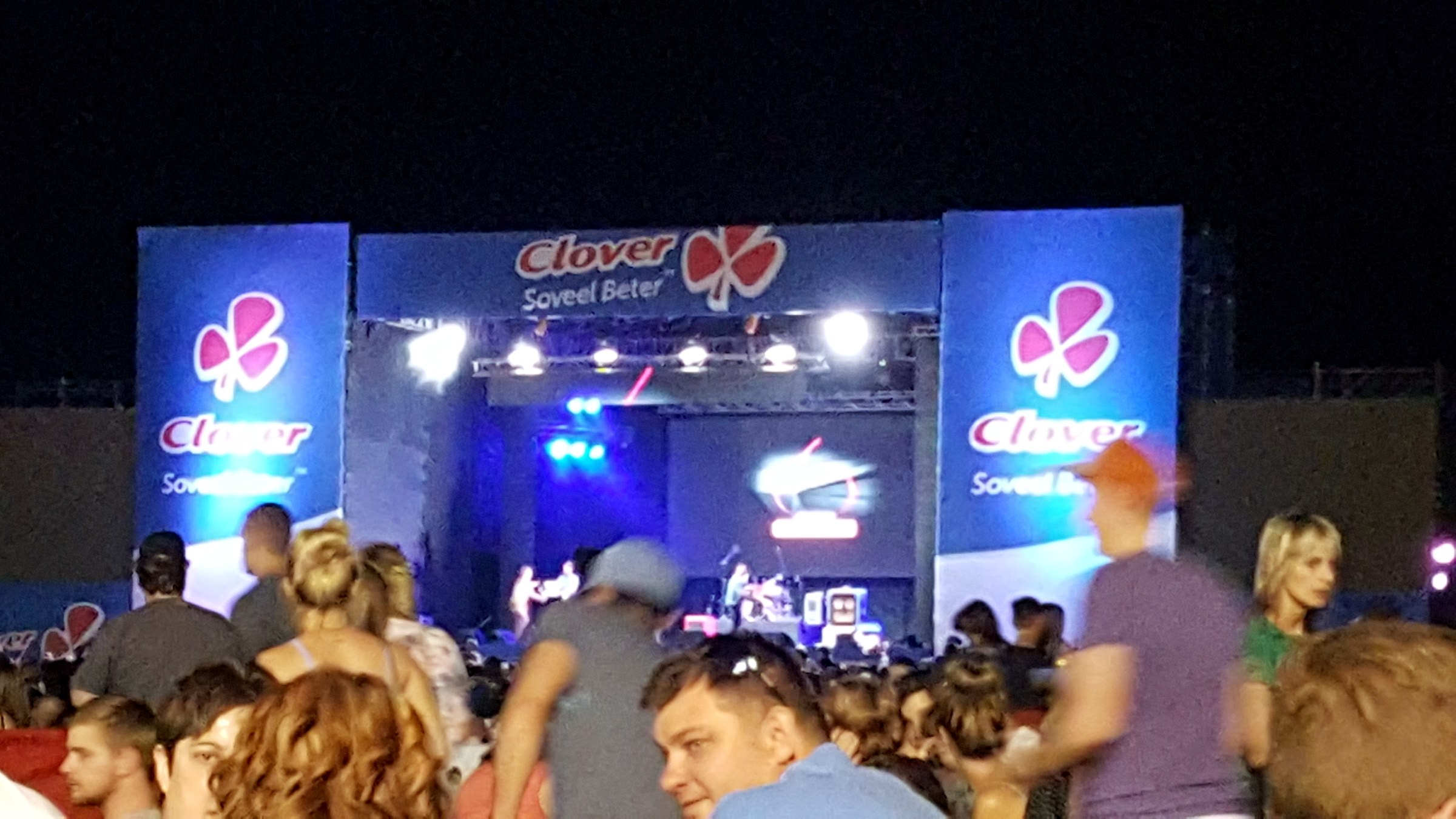 Outdoor stage at night with Clover Soveel Beter banners