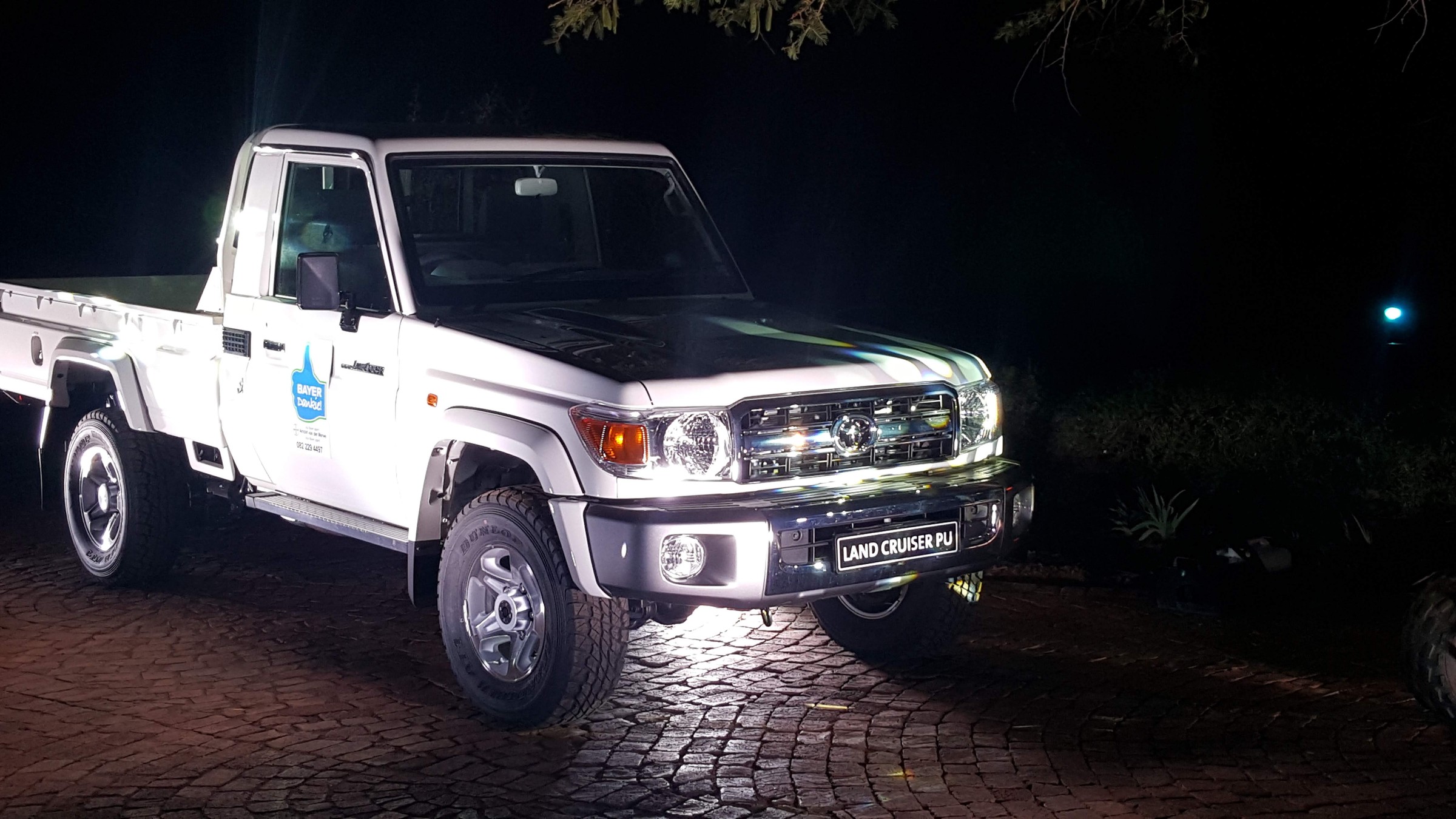 Close night view of a white Toyota Land Cruiser on cobble under product lighting