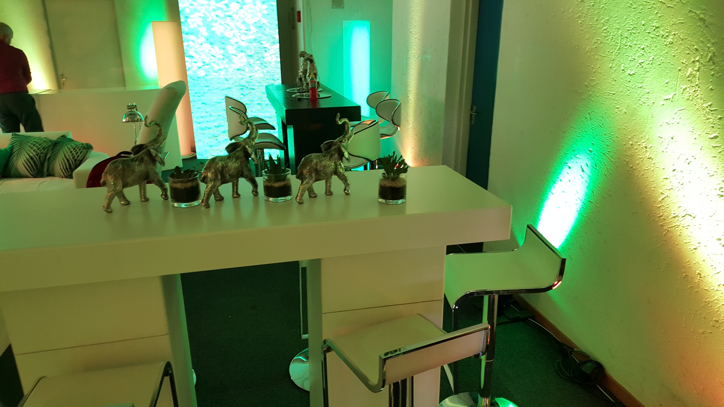 Cocktail tables with silver elephant sculptures and succulents under a green wash with blue light