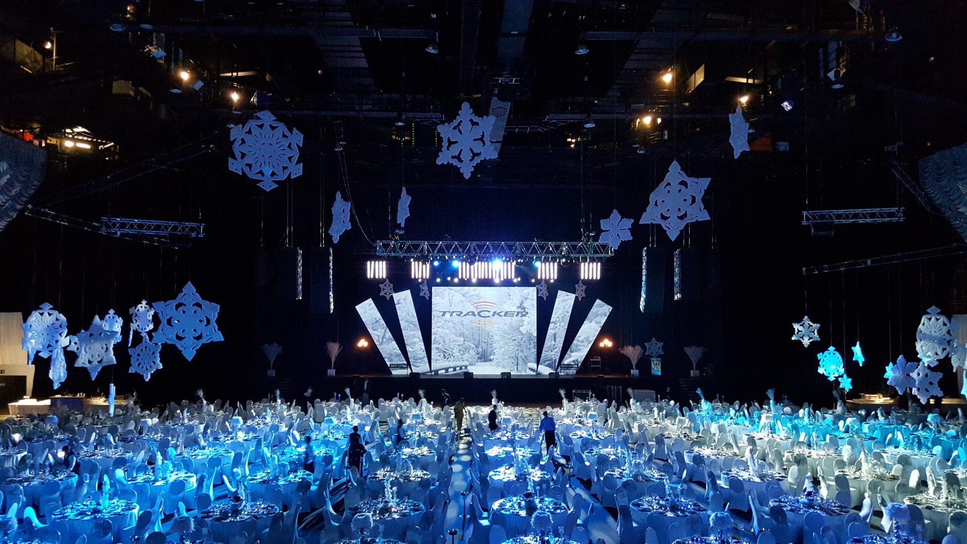 Dressed ballroom — white tables, blue wash, hanging snowflakes