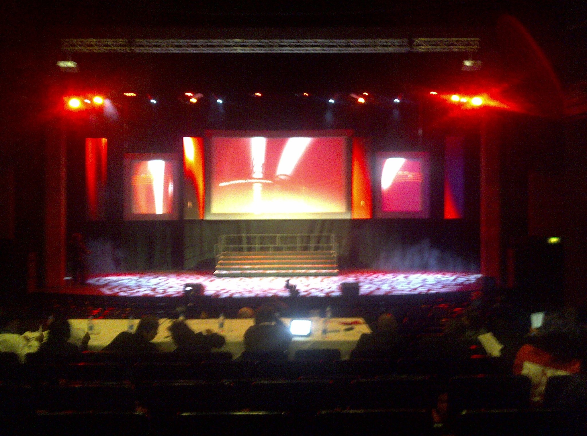 Live stage under a red wash with a tech desk in the foreground