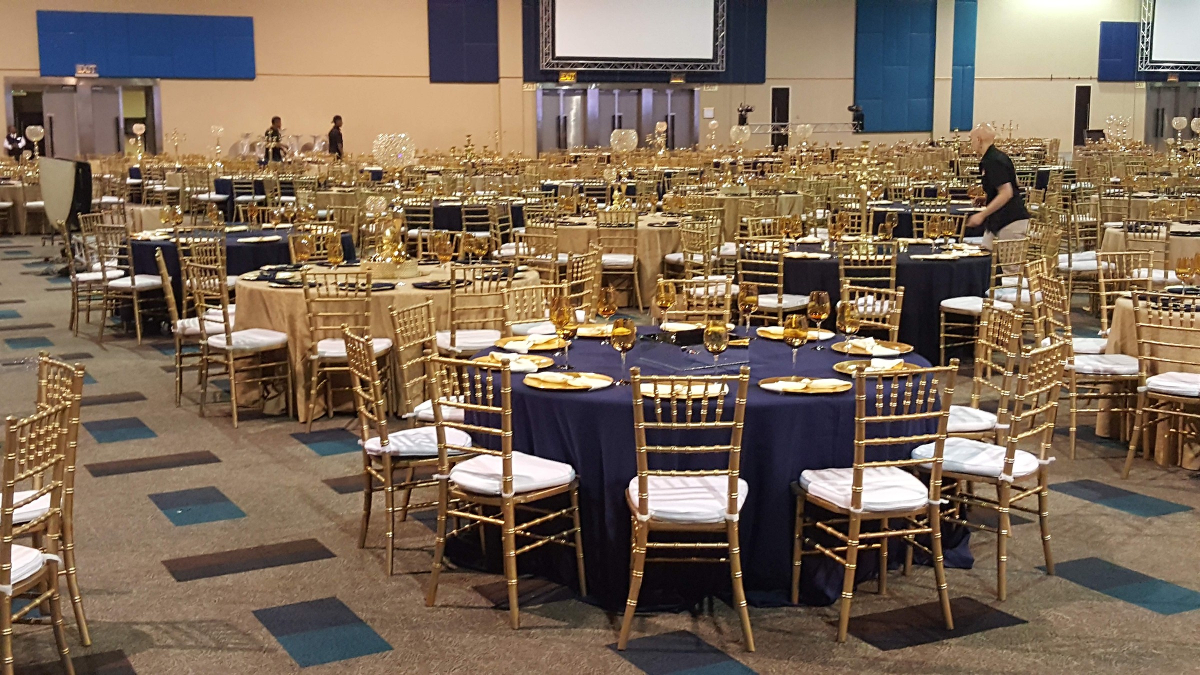 Banquet setup with navy and champagne linens, gold Chiavari chairs, candelabras, and crystal spheres