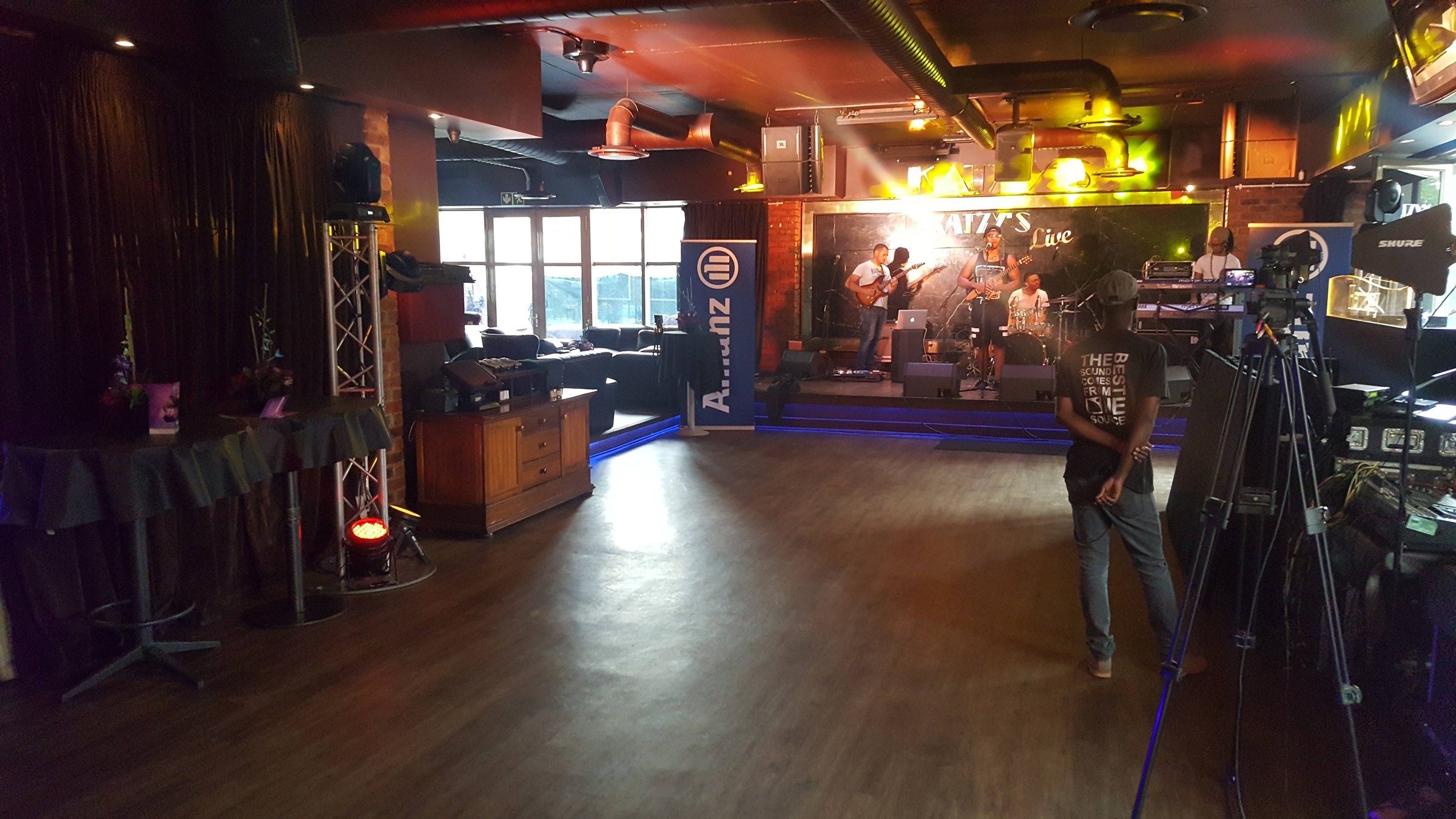 Allianz banner beside the Katzy’s Live stage with a band and blue LED lighting