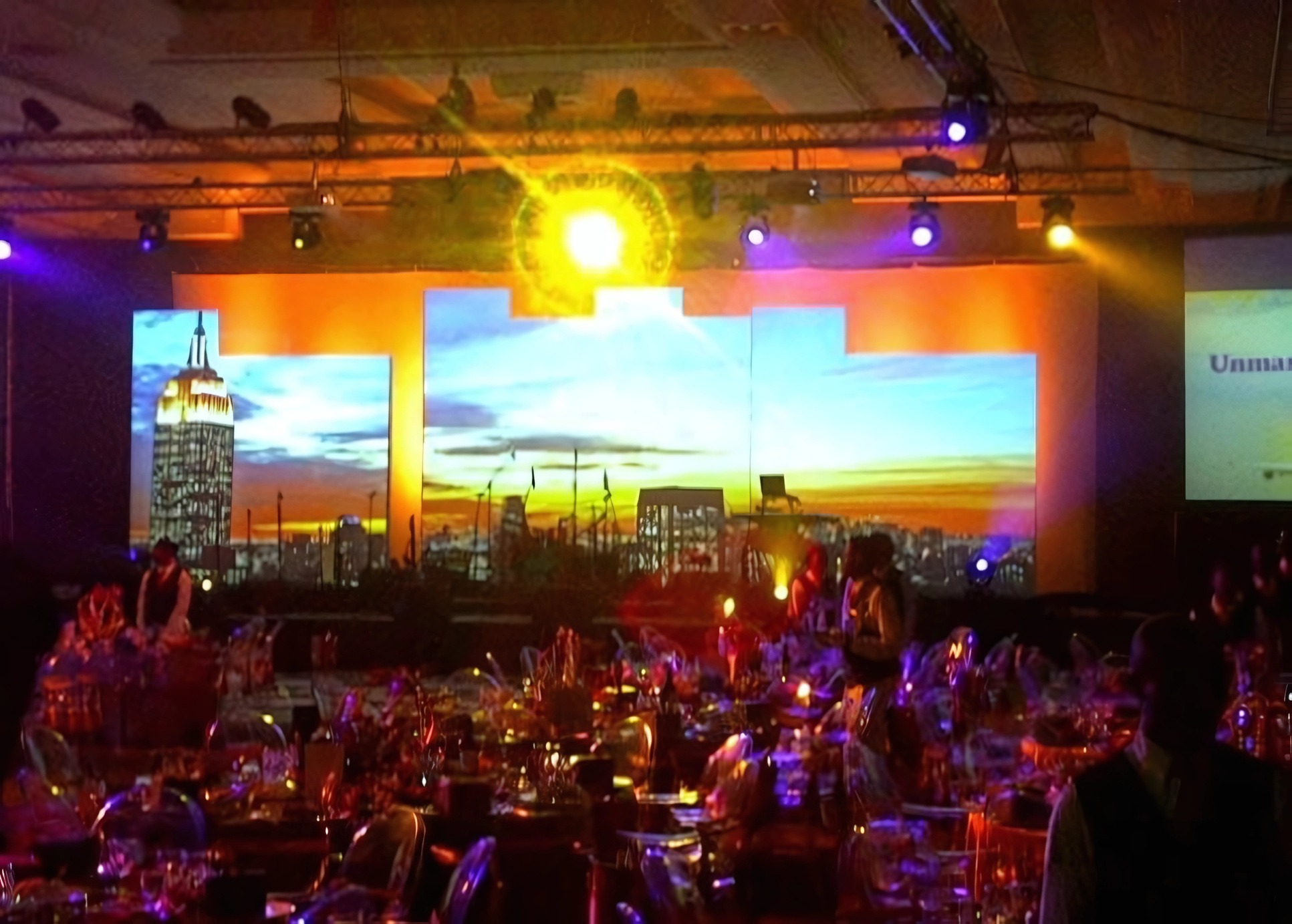 Banquet hall — stepped LED New York sunset skyline panels, blue and amber beams, ghost chairs